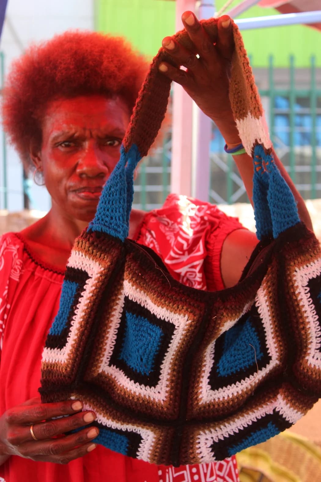Women holds up a bilum made from wool